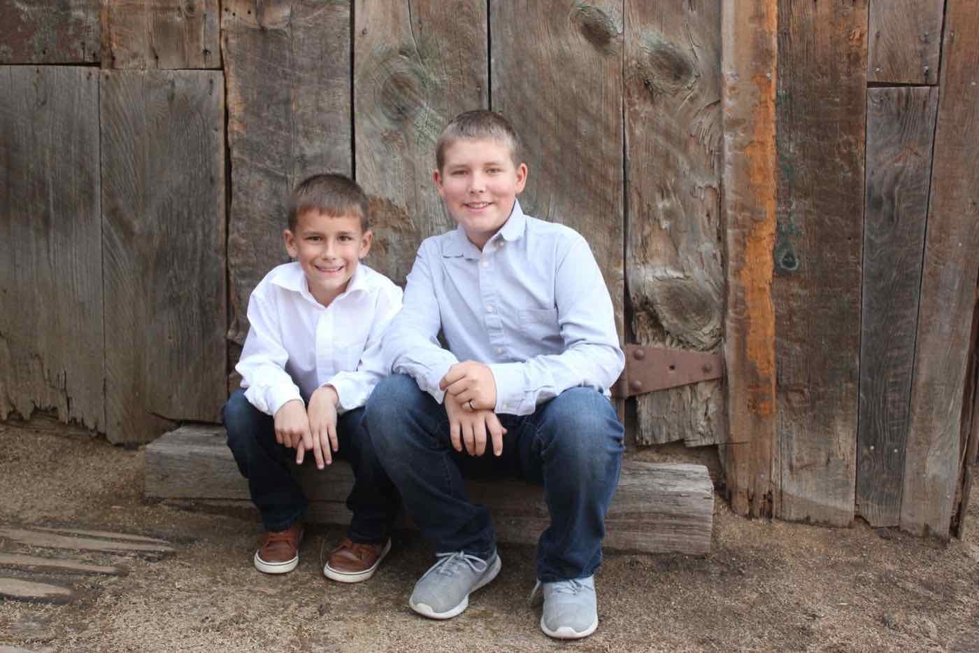 Zachary and Blake Been sitting on a wood step in front of an old barn wall