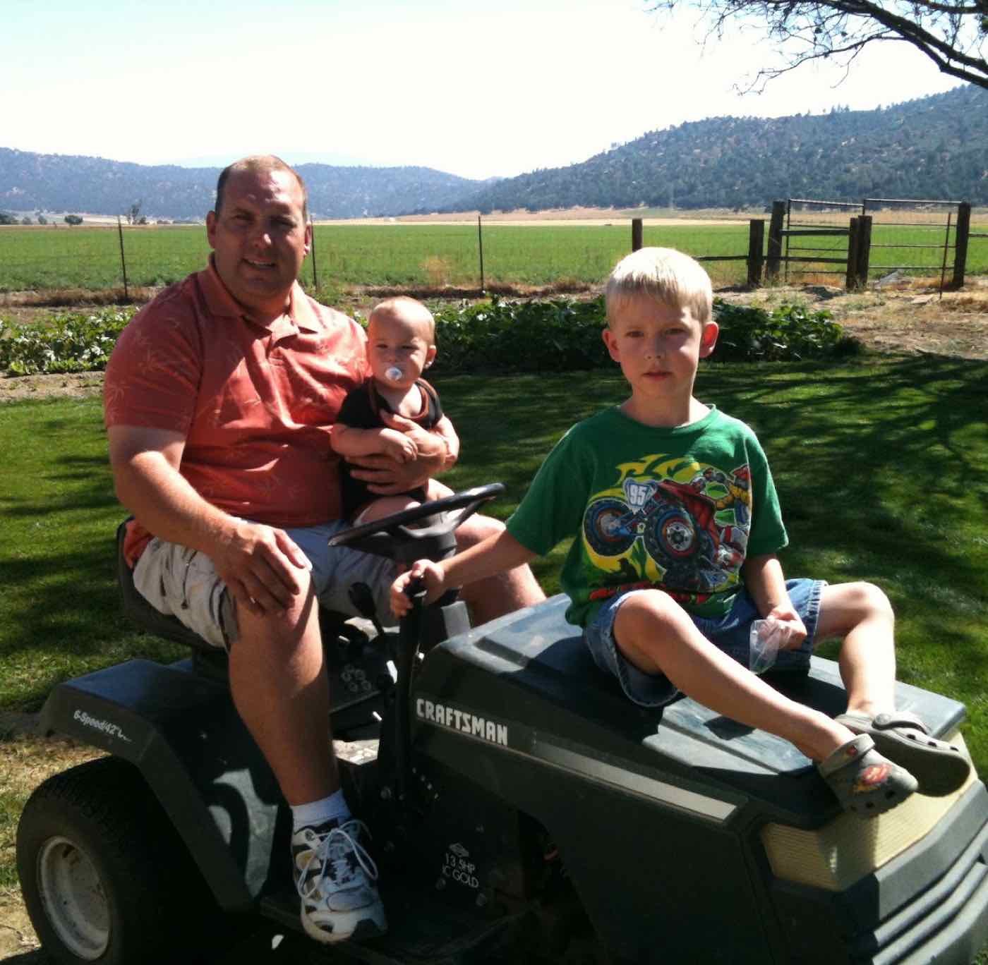 Allen on the riding mower with young Blake on his lap and Zachary on the hood