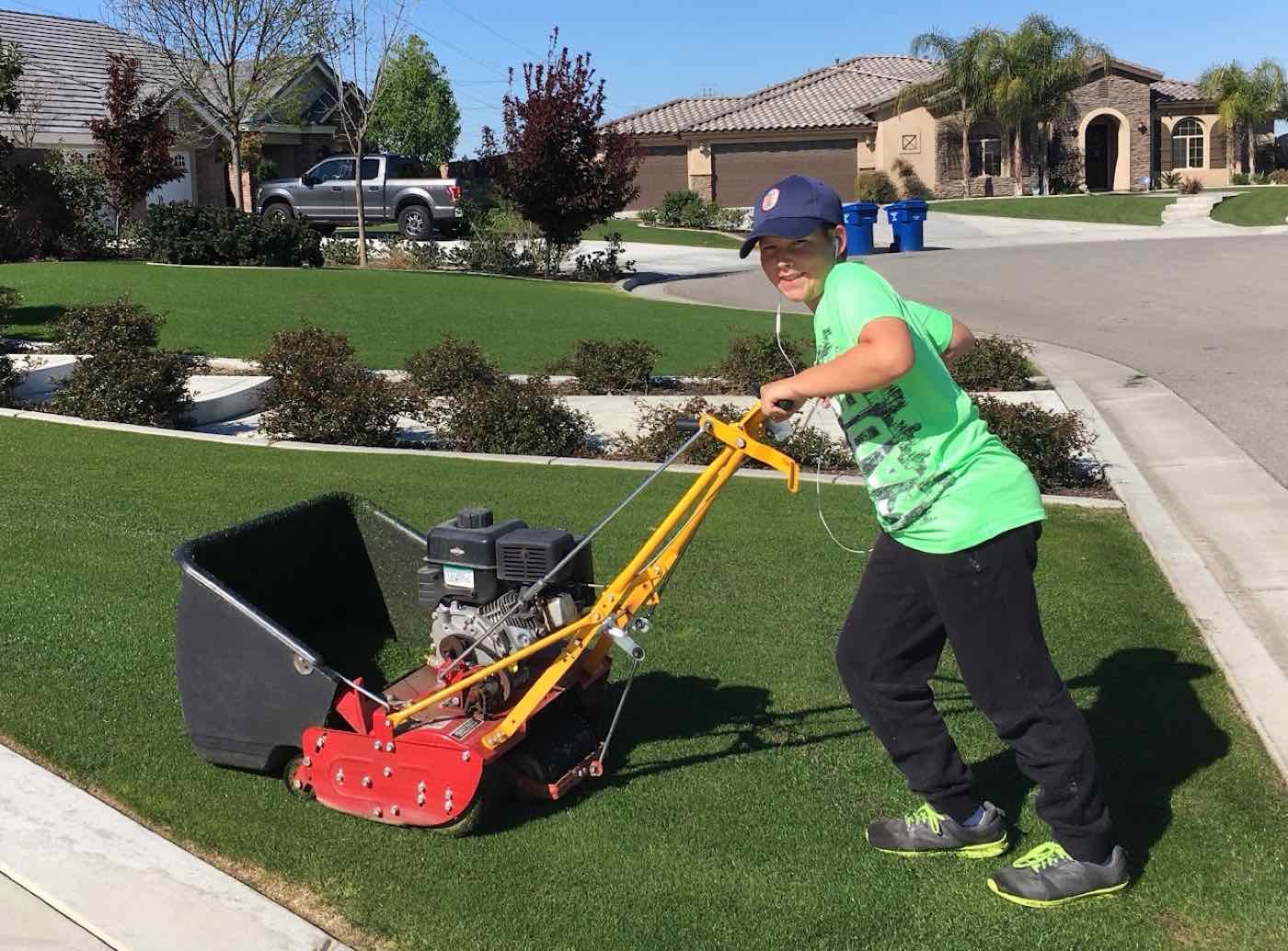 Zachary mowing a neighborhood front lawn with a reel mower