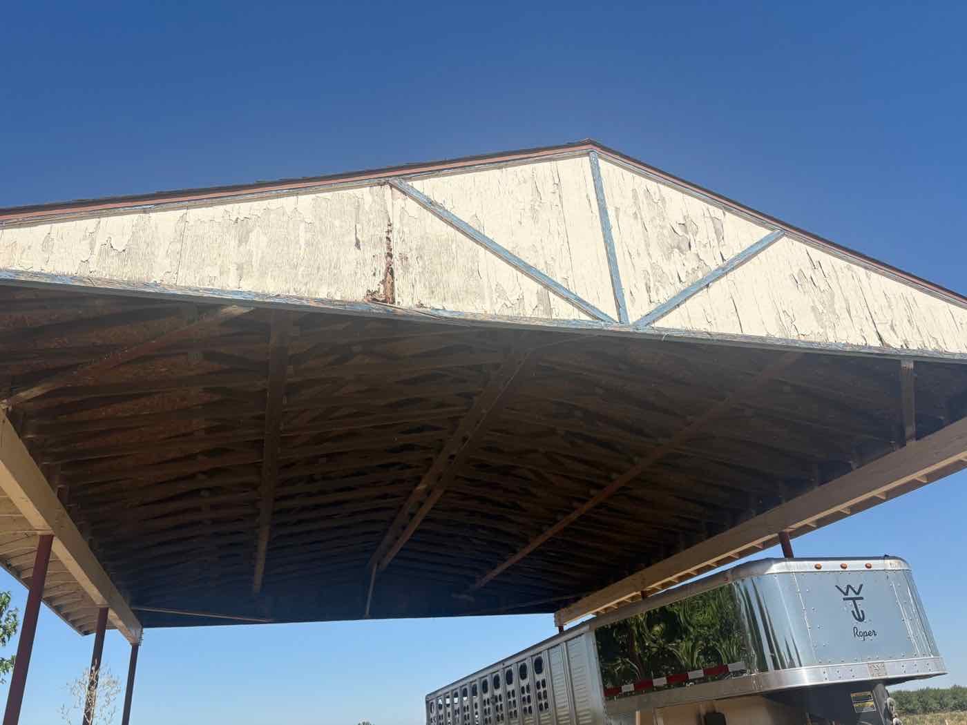 Open equipment cover with badly peeling white paint and worn blue trim on the gable, before repainting