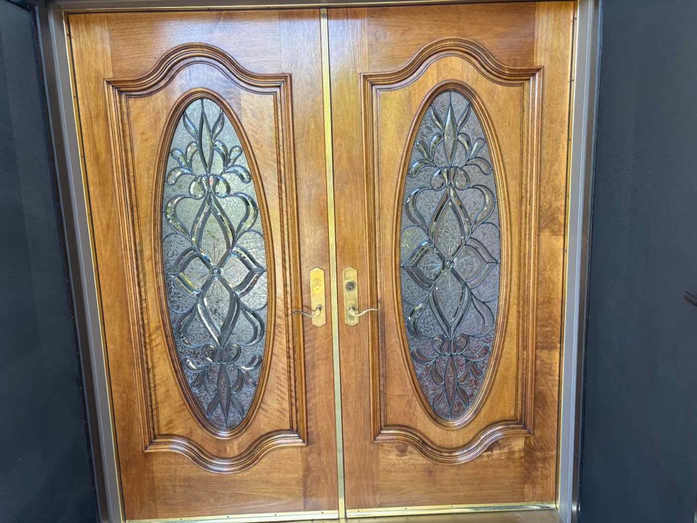 Refinished wood double doors with oval leaded glass inserts and a rich warm stain