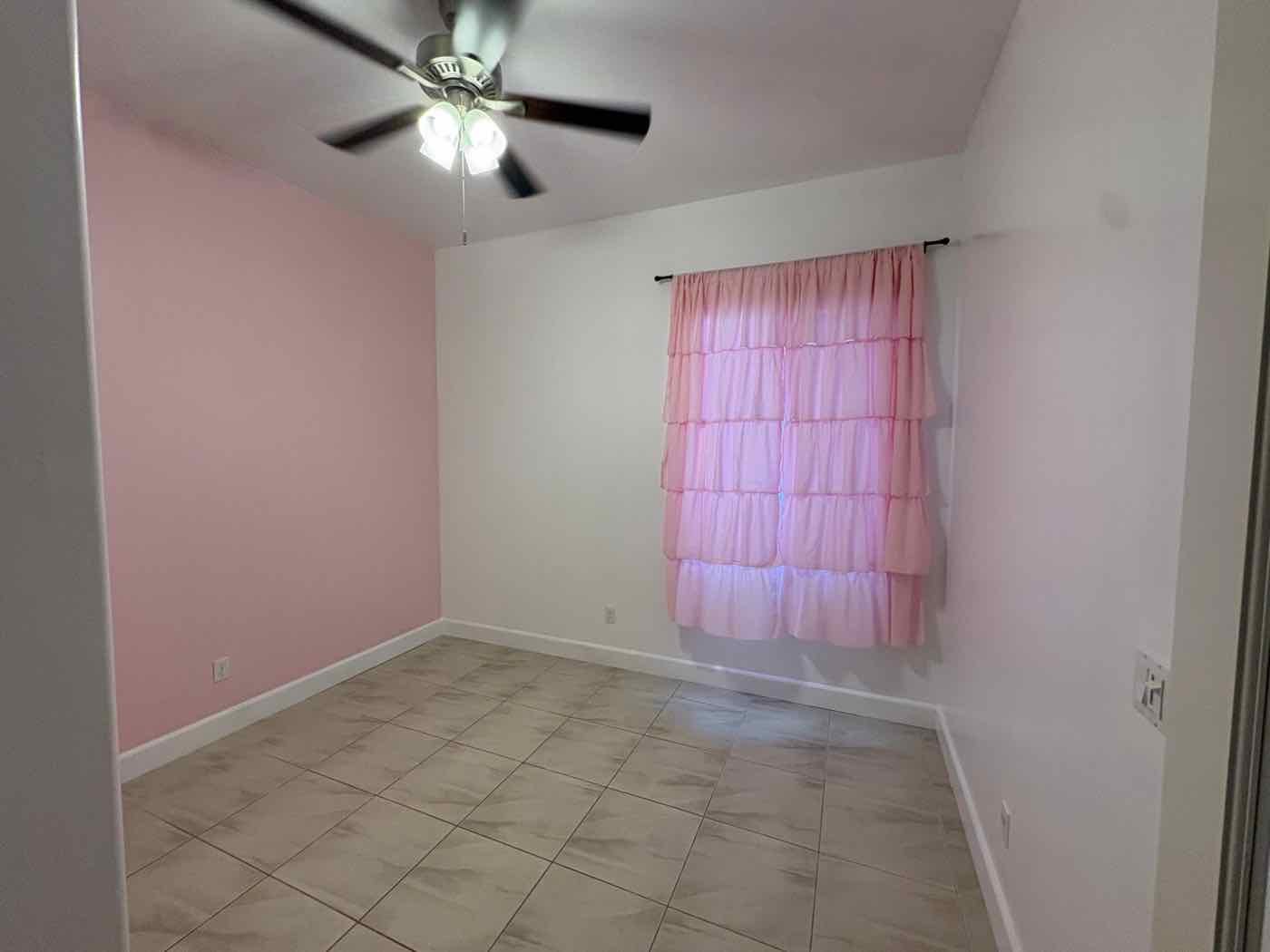 Bedroom with a soft pink accent wall, white walls and fresh white baseboards