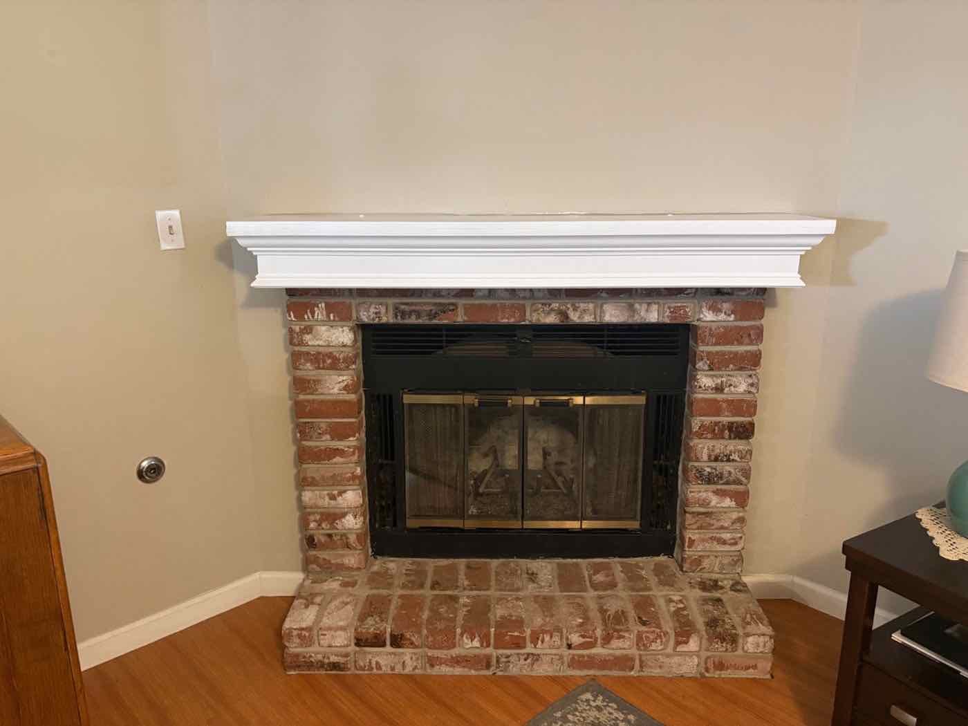Custom white painted mantel over a brick fireplace
