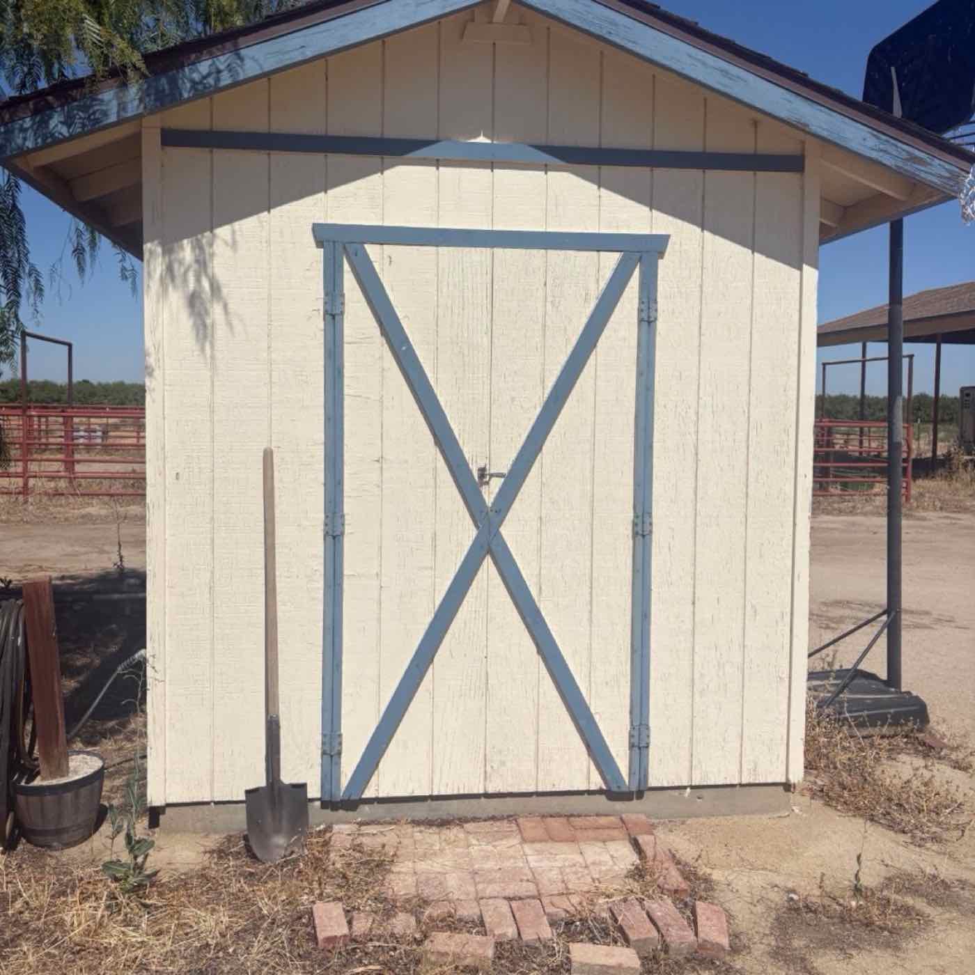 Storage shed before repainting: cream siding with faded blue trim